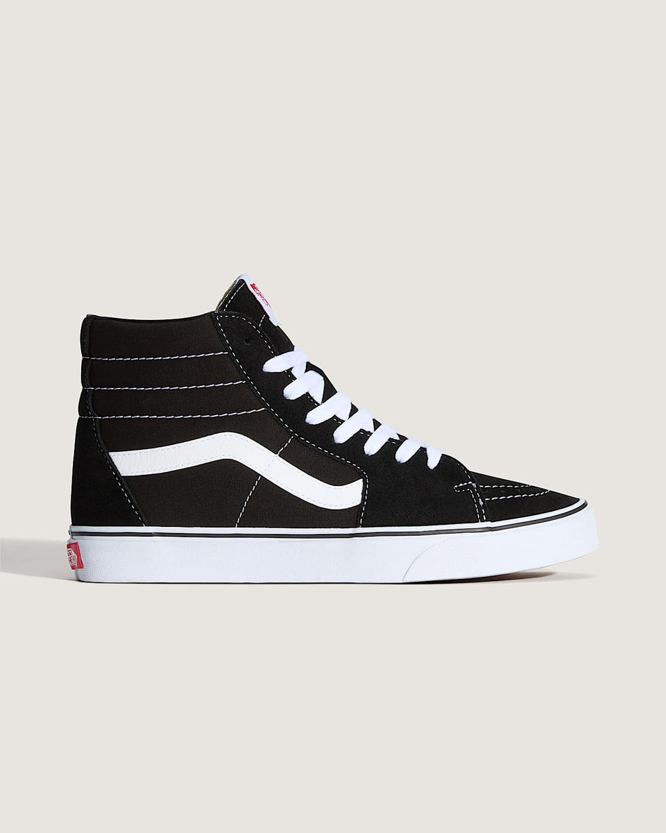 Black high-top sneaker with white laces on a light beige background