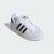 White Adidas sneaker with black stripes on a light gray background