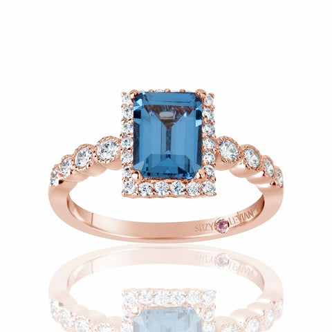 Rose gold ring with a blue gemstone and diamond accents on a white background