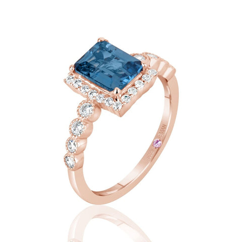 Rose gold ring with a blue gemstone and diamonds on a white background