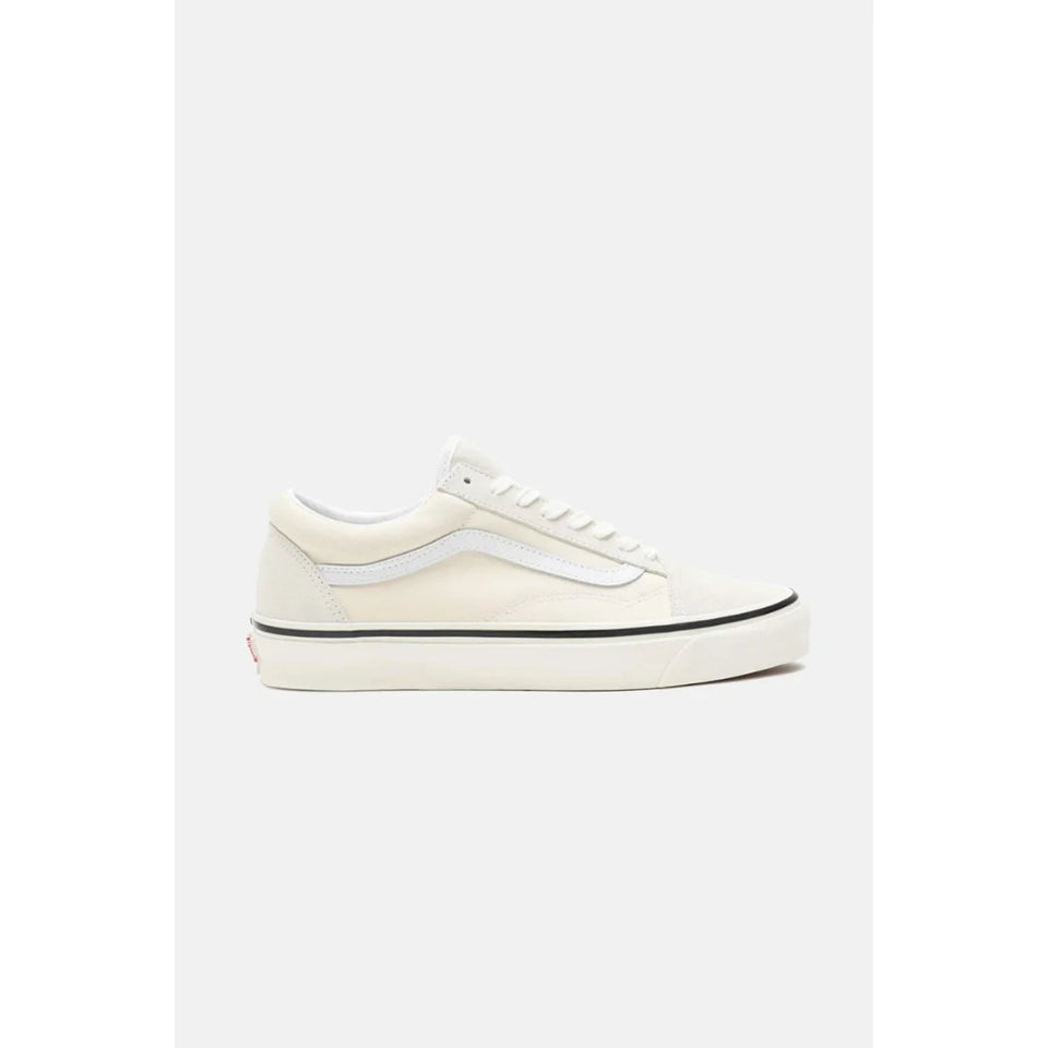 A classic low-top sneaker in off-white canvas with white laces, a white side stripe, and a black stripe along the midsole, shown from a side profile view against a light gray background.