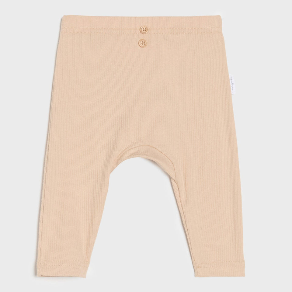 A pair of baby leggings in a light peach-beige color, featuring a ribbed texture, a buttoned waistband, and a small side tag, shown against a light gray background.