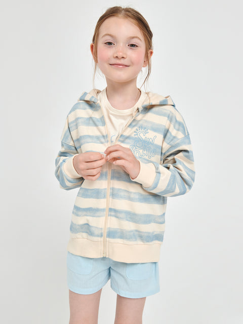 Young girl wearing a striped hoodie and shorts on a plain background