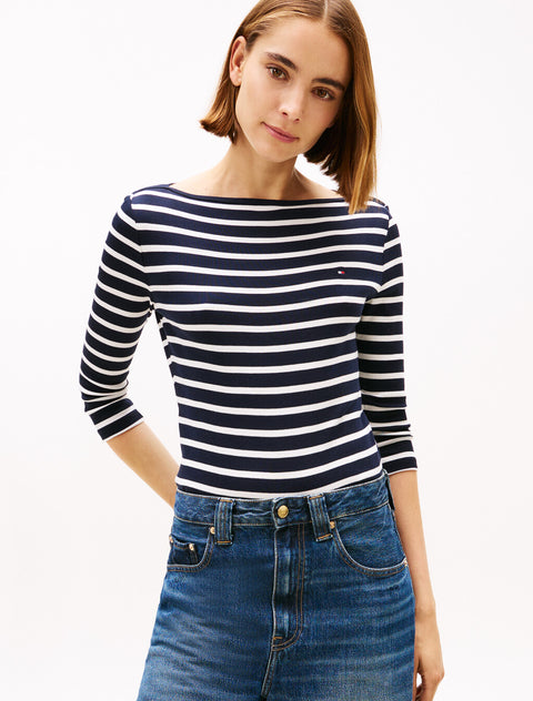 Woman wearing a navy and white striped long-sleeve top and blue jeans on a white background