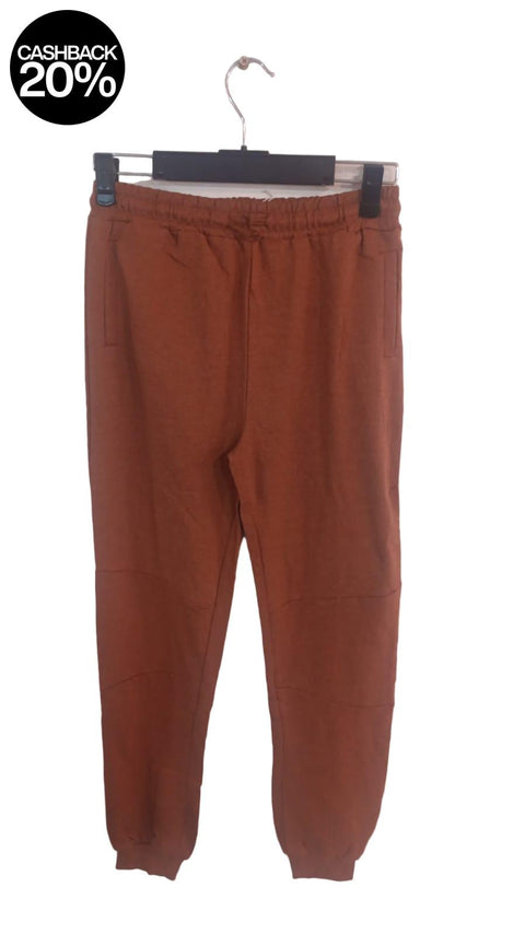 Brown sweatpants on a hanger against a light pink background