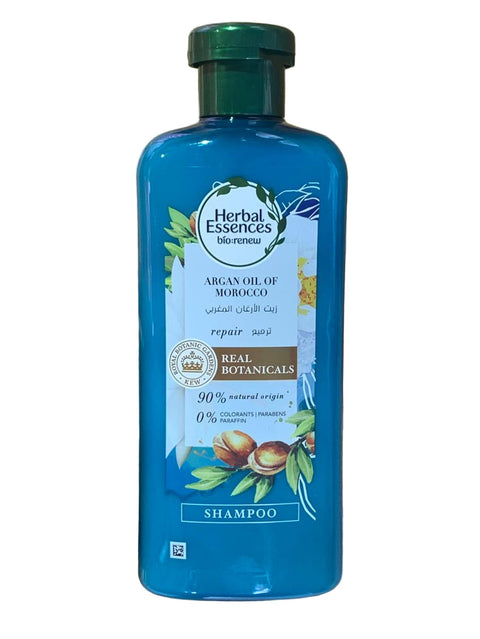 Hand holding a bottle of Herbal Essences shampoo with a natural background