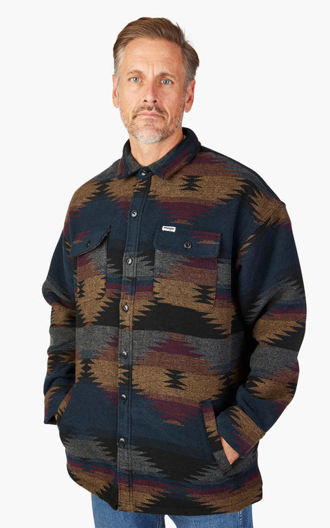 Man wearing a patterned shirt over a dark shirt on a white background