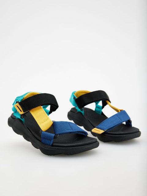 Pair of sandals with black, blue, and yellow straps on a white background