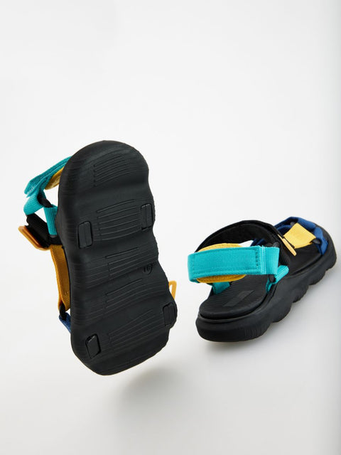 Black sandals with blue and yellow straps on a white background