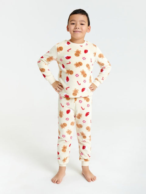 Child wearing pajamas with a gingerbread man pattern on a white background