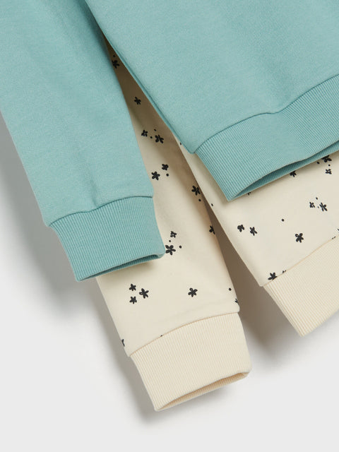 Two sweatpants, one light blue and one beige with black patterns, on a white background.
