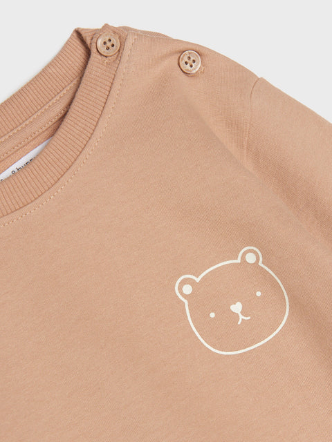Close-up of a brown garment with a white bear logo on a light gray background