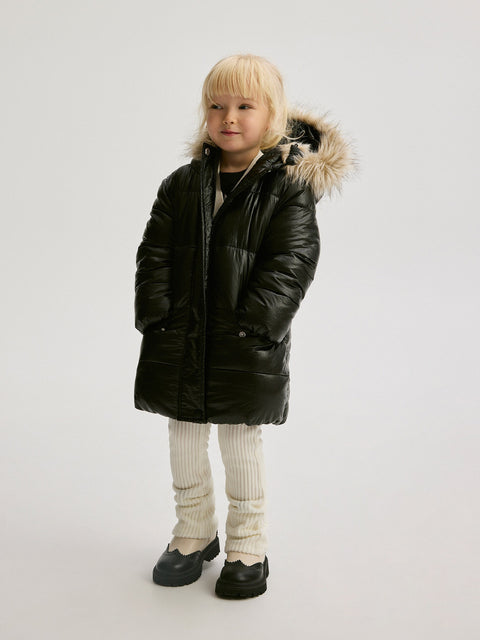 Child wearing a black winter coat with a fur-lined hood on a white background