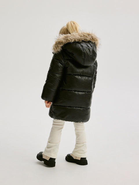 Person wearing a black puffer coat with a fur-lined hood on a white background