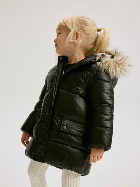 Child wearing a black puffer jacket with fur hood on a white background