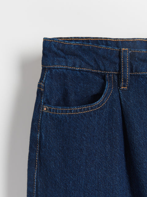 Close-up of a blue denim pocket on a plain background