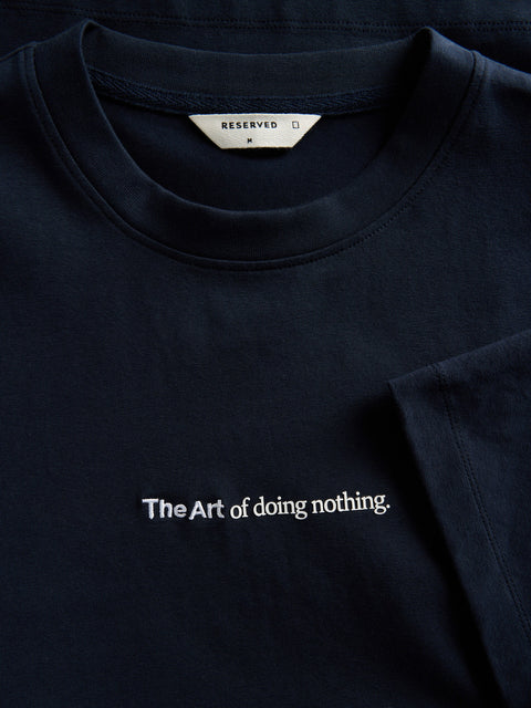 Navy blue t-shirt with 'The Art of doing nothing.' text on a plain background