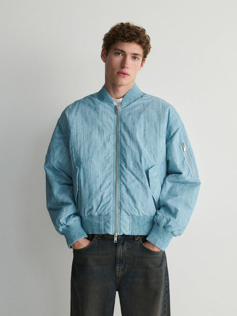 Person wearing a light blue jacket against a plain background