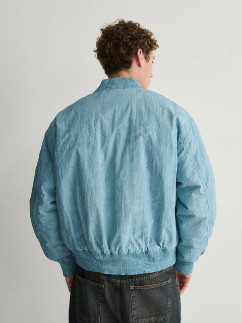 Person wearing a light blue jacket against a plain background