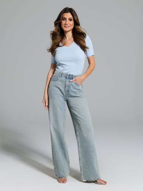 Woman wearing light blue jeans and a matching top on a gray background