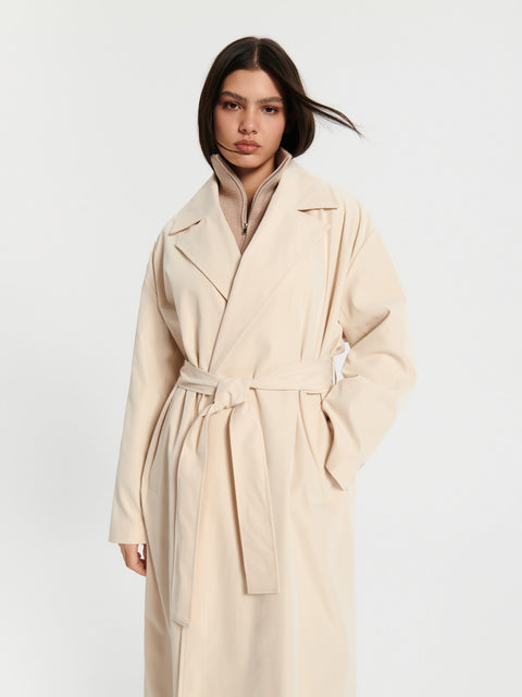 Woman wearing a beige trench coat on a white background