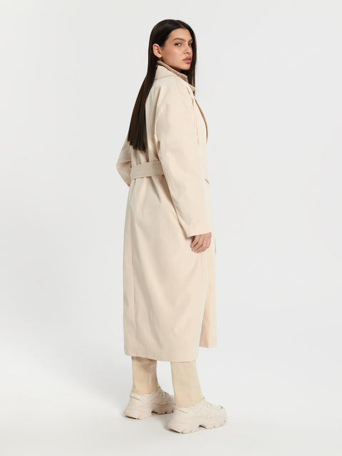 Woman wearing a beige trench coat on a white background