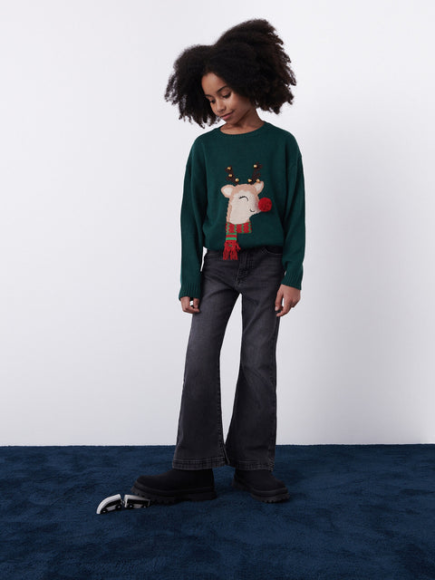Child wearing a green sweater with a reindeer design on a white background