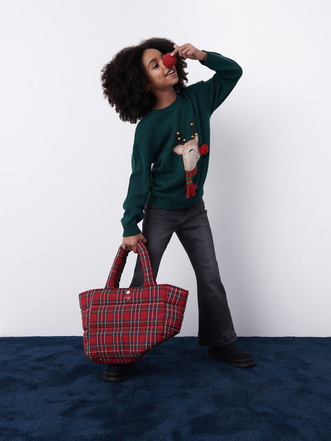 Person wearing a green sweater with a red bag on a white background