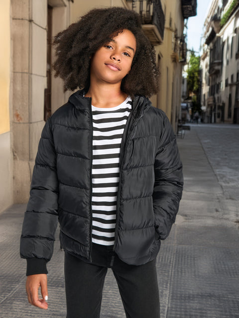 Person wearing a black puffer jacket over a striped shirt on a city street.