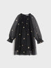 Black dress with gold star patterns on a light gray background
