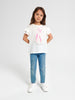 Young girl wearing a white t-shirt with a graphic design and blue jeans on a white background