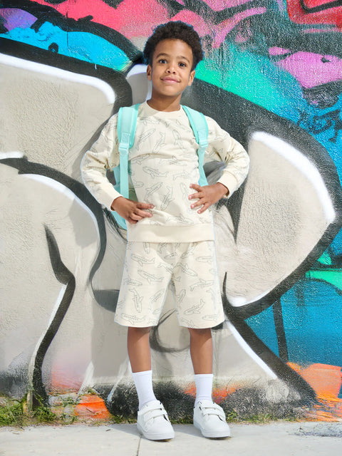 Child wearing a light-colored outfit with suspenders against a graffiti-covered wall.