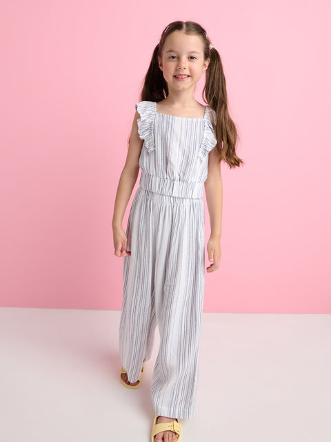 Young girl wearing a striped jumpsuit against a pink background