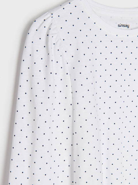 White long-sleeve shirt with black polka dots on a white background