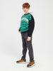 Child wearing a black and green patterned sweater with gray jeans on a white background