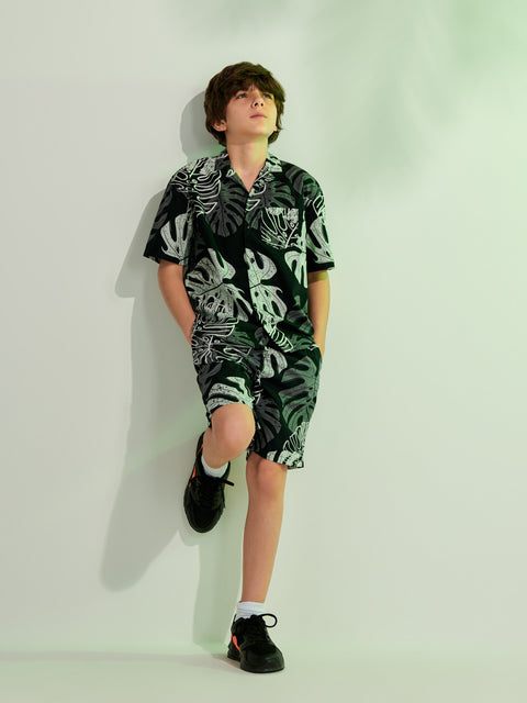 Person wearing a green and black patterned outfit against a white background