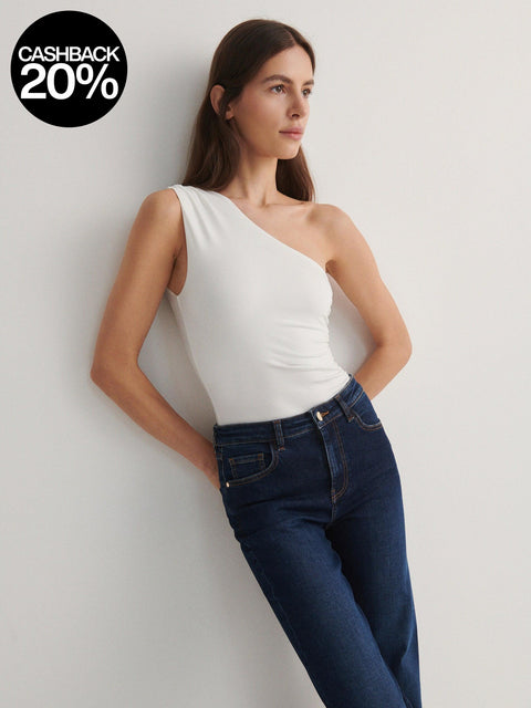 Woman wearing a white one-shoulder top and blue jeans against a light gray background with a cashback 20% offer.