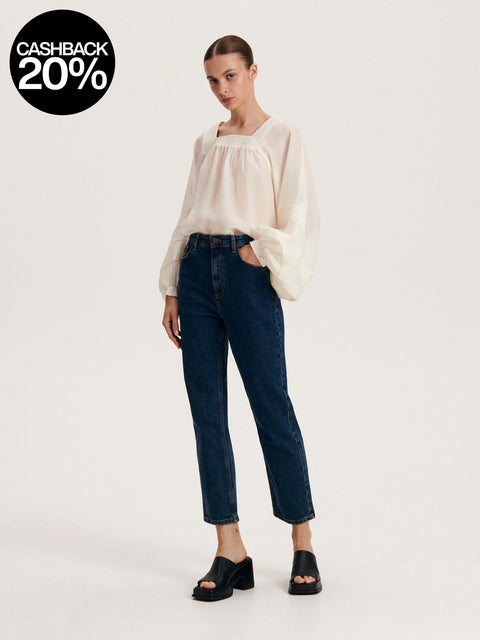 Woman wearing a white blouse and dark blue jeans on a white background