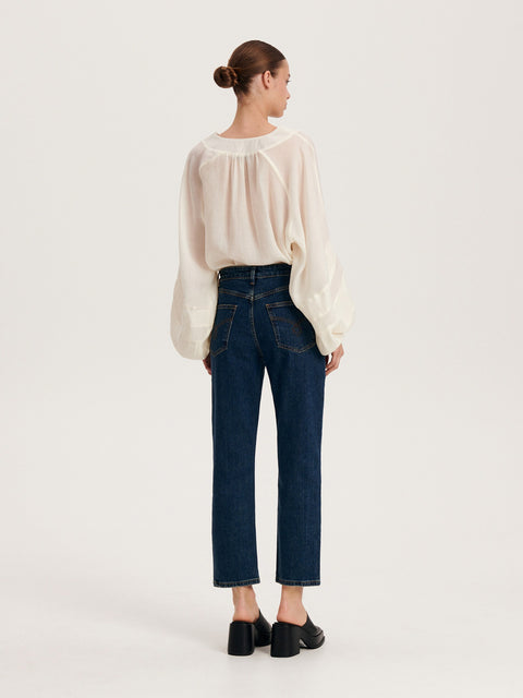 Woman wearing a white blouse and dark blue jeans on a white background