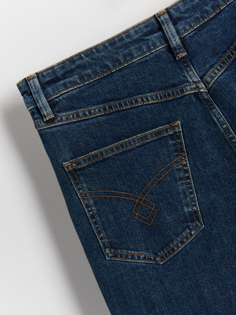 Close-up of blue jeans with a brand logo on the pocket against a light gray background