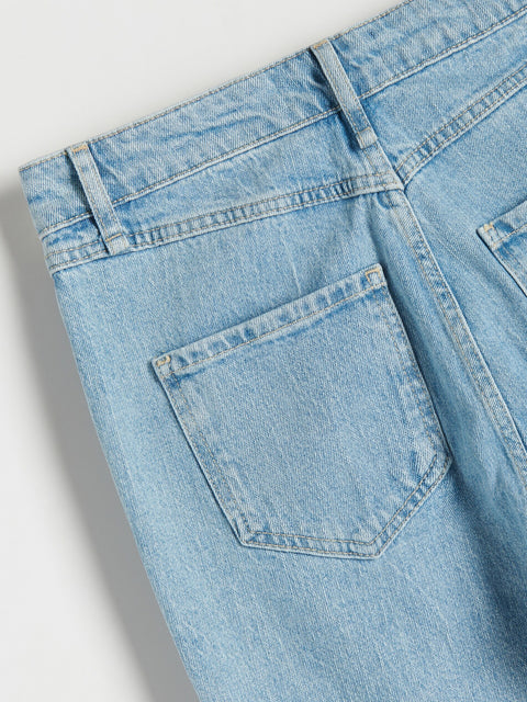 Close-up of light blue denim jeans with a pocket on a gray background