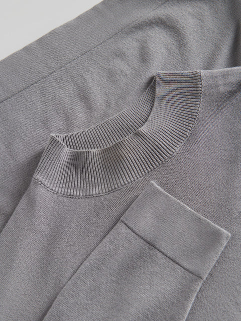 Close-up of a gray sweater with a ribbed neckline and pocket.