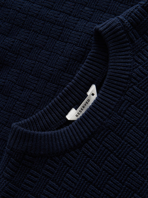 Close-up of a navy blue textured sweater with a 'Reserved' tag.