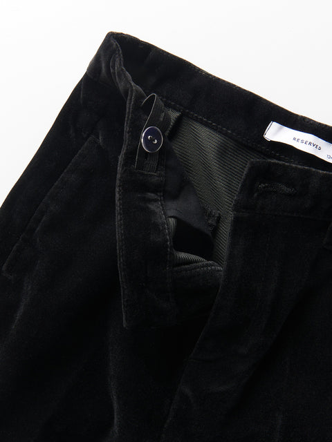 Close-up of black pants with a button and label on a white background