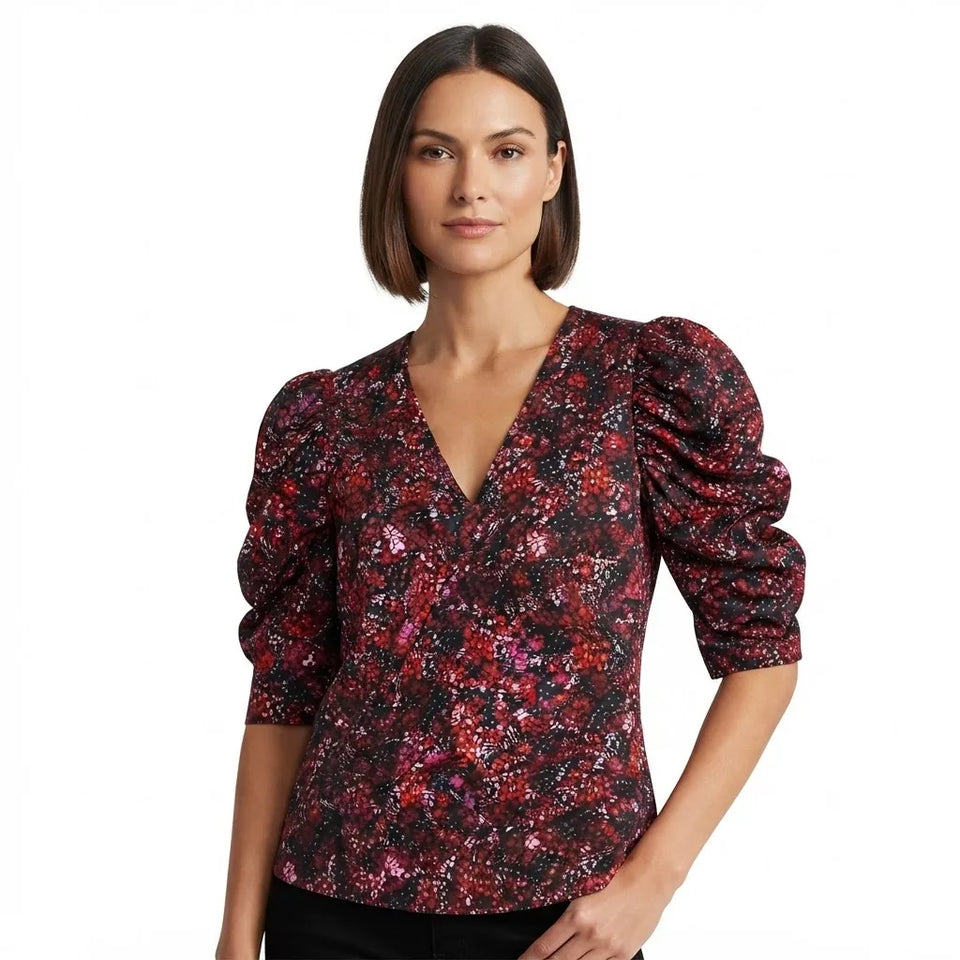 A woman wearing a dark red and black floral patterned blouse with puffed three-quarter sleeves and a V-neckline, shown against a plain white background.