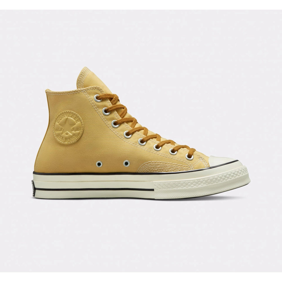 A single Converse high-top sneaker in a mustard yellow canvas finish, featuring matching yellow laces, a white rubber toe cap, and a cream-colored midsole.