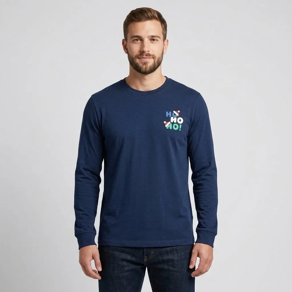 A man wearing a navy blue long-sleeve t-shirt with a colorful 'Ho Ho Ho!' graphic on the left chest, paired with dark blue jeans, against a light gray studio background.