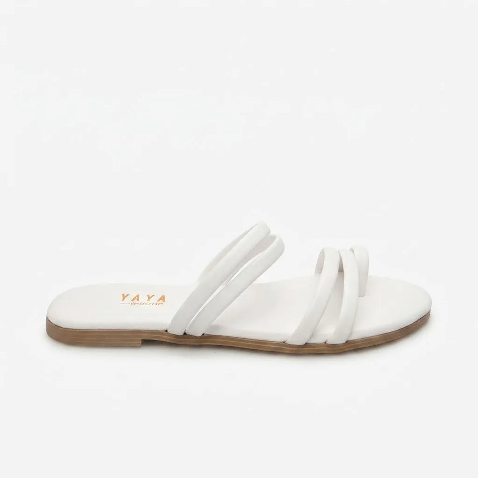 A white flat slide sandal with multiple thin straps and a tan sole, shown from a side profile on a light gray background. The brand name 'YAYA' is printed in orange on the footbed.