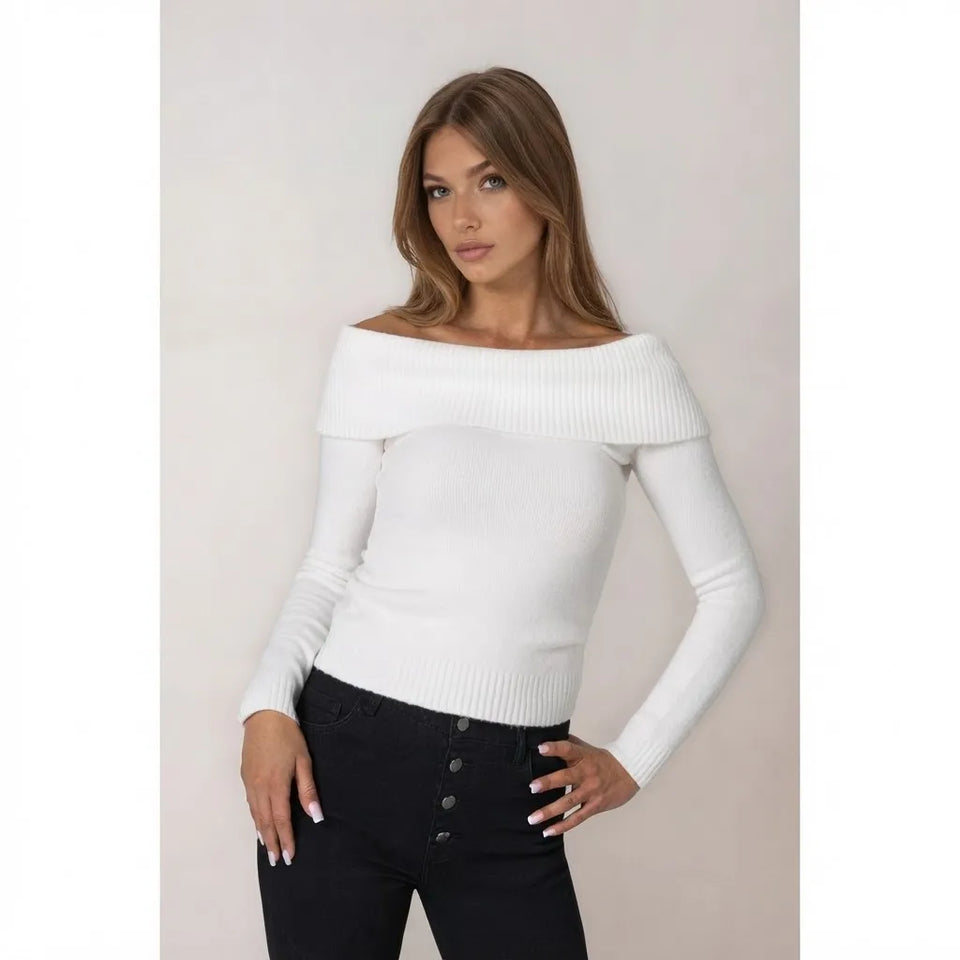 A woman modeling a white off-the-shoulder long-sleeve knit sweater paired with black pants, set against a plain light beige studio background.