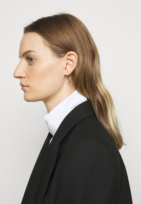 Person wearing a black blazer and white shirt against a plain background